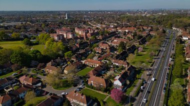 Evleri, ağaçları, parkı ve çok şeritli bir yolu olan bir banliyö mahallesinin hava görüntüsü. Morden, Londra, İngiltere 'de şehir silüeti.