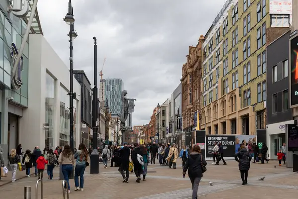 Leeds, İngiltere 'de binaları, dükkanları ve bulutlu bir gökyüzünün altında heykeli olan kalabalık bir yaya caddesi..