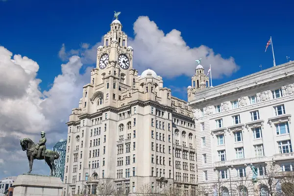 Liver Binası 'nın alçak açılı görüntüsü saat kuleleri, bitişik beyaz bina, at heykeli, Liverpool, İngiltere' de bulutlu mavi bir gökyüzüne karşı..
