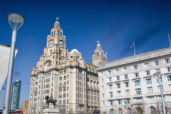 Liverpool 'un mimarisi, Royal Liver Binası dahil, parlak mavi bir gökyüzünün altında. Önplanda ışık direği