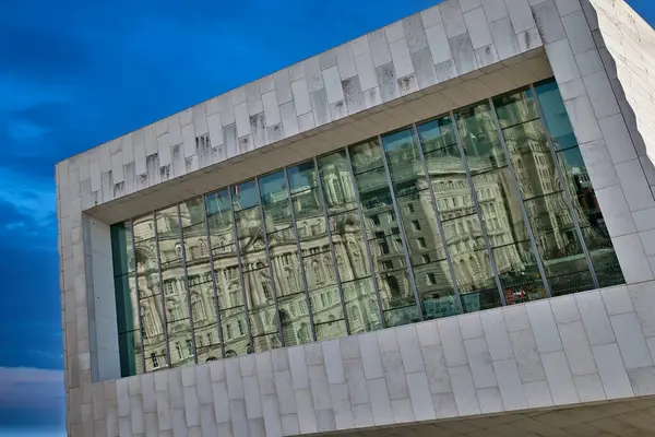 Liverpool, İngiltere 'de mavi gökyüzüne karşı klasik mimariyi yansıtan büyük cam pencereli modern bina cephesi.
