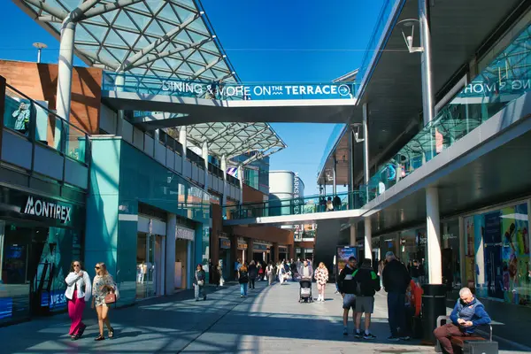 Açık hava alışveriş merkezi sahnesinde Liverpool, İngiltere 'de açık mavi gökyüzü altında dükkanlar, insanlar ve yükseltilmiş geçitler yer alıyor..