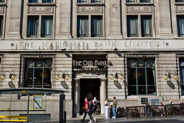 Açık gri taştan bir bina, eski adıyla Ulusal Banka, şimdi Eski Banka. İngiltere, Liverpool 'da insanlar kaldırımda yürür..