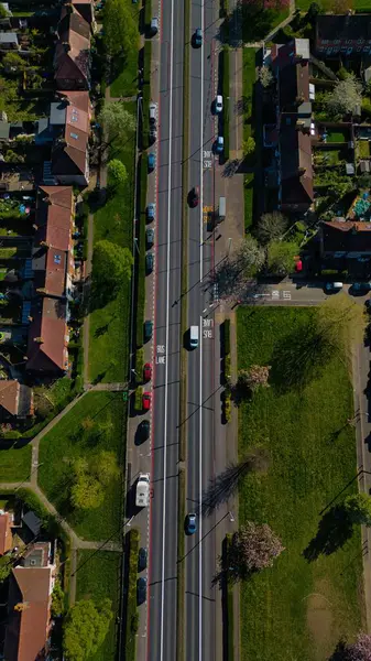 Morden, Londra, İngiltere 'de evler ve yeşil alanlarla çevrili çok şeritli bir yolun hava manzarası..