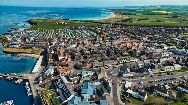 Çeşitli binaları, marinası, plajı ve çevresindeki tarım arazileri olan kıyı kasabasının havadan görünüşü, İngiltere 'nin Deniz Evleri köyündeki yerleşim, ticari ve doğal unsurların bir karışımını gösteriyor..