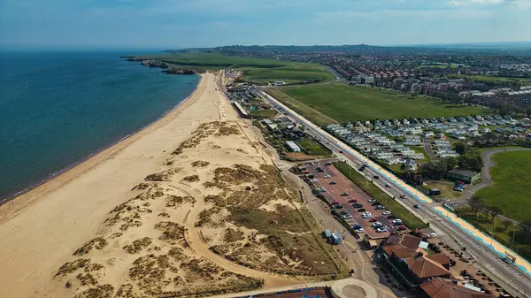 Kumsal, kum tepeleri, yollar, binalar, otoparklar ve Sandhaven Sahili 'nde bulutlu mavi gökyüzü altında bir kasaba..