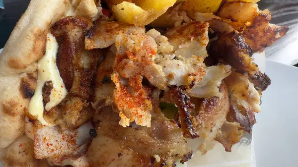 Izgara et, patates kızartması, sos ve baharatlı jiroskoplu sandviç. Kompozisyon sıkıca çerçevelenmiş, dokular ve malzemeler vurgulanmış..