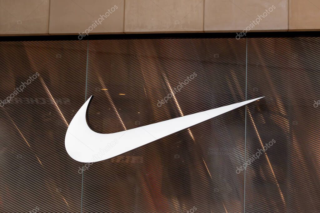 A large, white Nike swoosh logo is prominently displayed against a textured, brown background with vertical divisions.