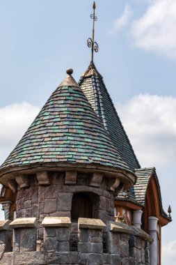 Fransa 'nın Disneyland şehrinde, bulutları dağılmış açık mavi bir gökyüzüne karşı taş duvarları ve kiremitli çatıları olan iki kale kulesine yakın çekim..