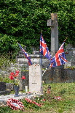 Birlik bayrakları, gelincikleri ve Fransa 'nın Giverny kentindeki yeşillik ve diğer mezar taşlarıyla çevrili bir mezarlıkta savaş anıtı..