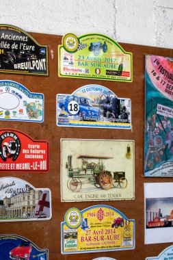 Ahşap bir yüzeye yapıştırılmış renkli otomotiv ralli çıkartmaları ve plaketleri koleksiyonu. Giverny, Fransa 'da tarih 20. yüzyılın başlarından 2019' a kadar değişiyor..