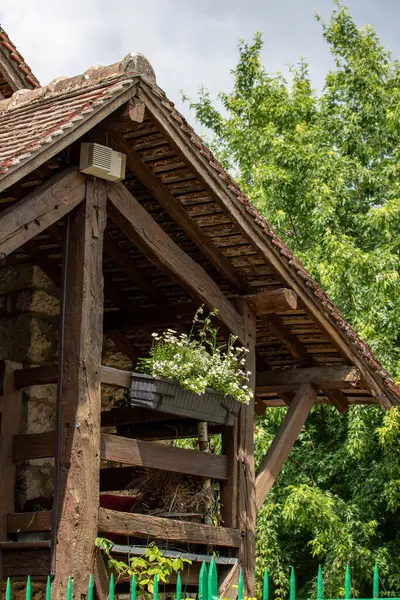 Fransa 'nın Giverny kentindeki yeşil bir yaprak zeminine bakan, fayanslı çatısı olan, bir çiçek kutusuna sahip eskimiş ahşap bir yapının yakın çekimi..