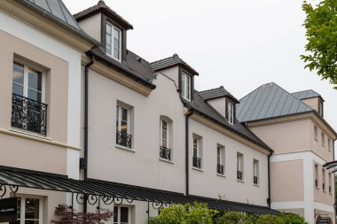 Yurtlu çok katlı binalar, bej duvarlı Avrupa tarzı mimari sergileniyor ve Fransa 'nın La Vallee Köyü' nde koyu çatılar var..