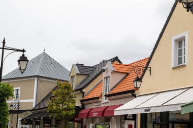 Fransa 'nın La Vallee Köyü' nde çeşitli çatı stilleri, tenteleri ve bulutlu gökyüzü altındaki renkleri olan dükkanlar..
