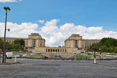 Görüntü Fransa, Paris 'teki Palais de Chaillot' u gösteriyor, bulutlu mavi bir gökyüzünün altında. Öndeki kaldırım taşı caddesi..