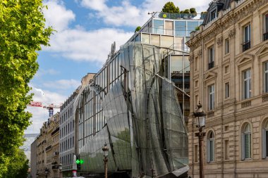 Modern cam cephe ve klasik bina cephesi de dahil olmak üzere kendine özgü mimarisi olan binaların mavi gökyüzüne bakan görüntüsü..