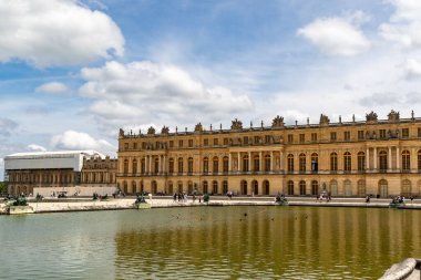 Bulutlu bir gökyüzünün altında gölle birlikte Versailles Sarayı 'nın manzarası. Sarayın bir kısmı onarıldı ve kapatıldı..