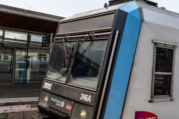 İstasyonda bir trenin ön cephesine yakın çekim. Açık mavi aksanlı siyah bir önü var. Tren detayları ve istasyon ögeleri görünür.