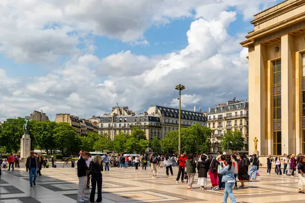 Mimarinin yer aldığı açık hava manzarası, insanlarla dolu bir plaza ve Paris 'te parçalı bulutlu bir gökyüzü..