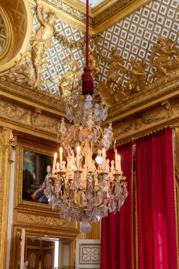 Paris, Versailles Sarayı 'nda kristal bir avize, altın rengi bir detay, bir tablo ve kırmızı perdeler içeren görkemli bir iç çekim..