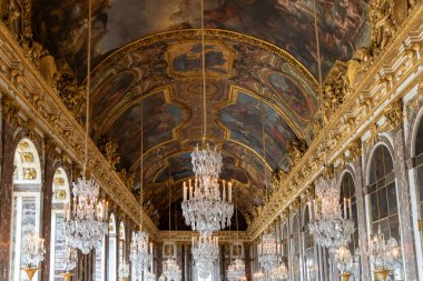 Boyanmış tavan, altın rengi detaylar, kemerli pencereler ve Paris Versailles Sarayı 'nda çoklu kristal avizeler bulunan süslü bir salon..