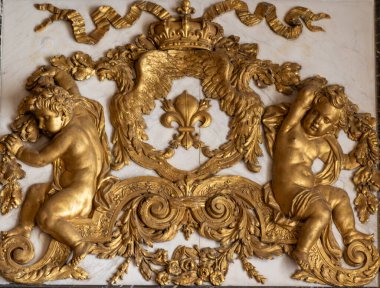 Beyaz mermer bir arka planda meleklerin, zambakların, tacın ve kartalların yer aldığı süslü yaldızlı bir rahatlama. Paris 'teki Versailles Sarayı' nda ayrıntılı detaylar vurgulandı.