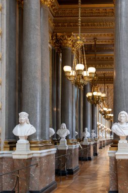 Taştan sütunlar, portre büstleri, süslü tavanlar ve Paris 'teki Versailles Sarayı' nda asılı avizelerden oluşan uzun bir koridorun iç manzarası..