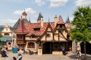Parlak bir günde parktaki fayanslı çatısı olan hayali, renkli binaların dış görüntüsü. İnsanlar Disneyland Paris 'te yürüyorlar..