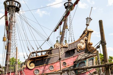 Bir korsan gemisinin ön cephesinin alçak açılı görüntüsü. Altın tomarlı kırmızı ve siyah odun, direkler, donanım ve fener detaylarıyla Disneyland Paris 'te parlak bir gökyüzü altında.