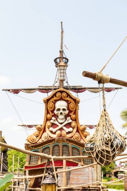 Kafatası, çapraz kemikleri, ipleri, direği olan ve Disneyland Paris 'te parlak bir gökyüzüne karşı ağ ören kısmen görünür bir korsan gemisi yapısı..