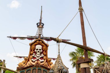 Görüntü, kafatası ve çapraz kemikli bir korsan gemisinin kıç tarafının Disneyland Paris 'te soluk mavi bir gökyüzüne çarptığını gösteriyor..