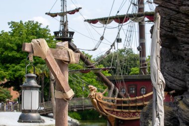 Fenerler, direkler ve yelkenler, halat aksanları ve arka planda yeşil yapraklar içeren korsan gemisi detayları Disneyland Paris 'te mavi bir gökyüzünün altında.