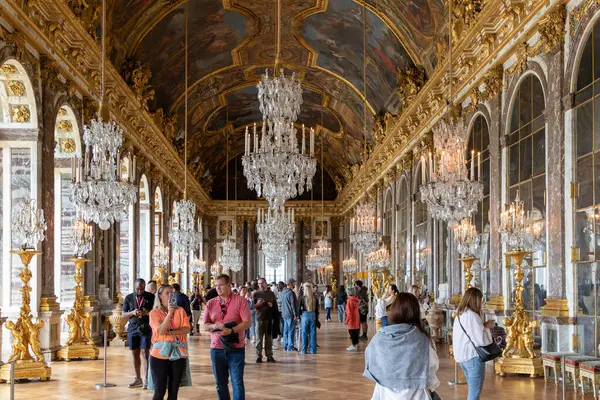 Versay 'daki Aynalar Salonu ziyaretçilerle dolu. Tavandan sarkan avizeler aynalı duvarlara yansıyor..