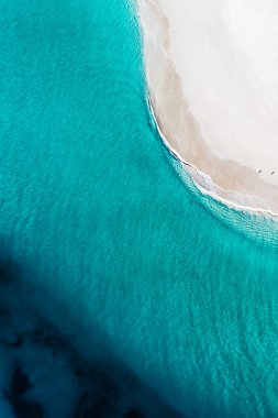 Güzel tropikal turkuaz okyanus sularının sığ dalgalı havadan görüntüsü. Yazın duvar kağıdında parlak, güneşli bir gün. Deniz manzaralı arka plan. Kıyı duvar kağıdı. Mavinin okyanus tonları