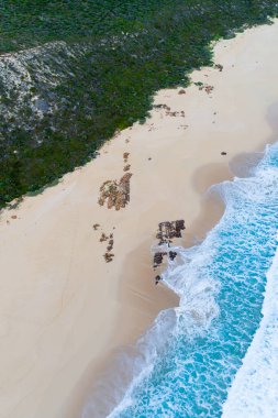 Havadan kumsal manzarası ve berrak mavi su. Sahildeki okyanus dalgaları arka planda kalıyor. Güzel doğal yaz tatili geçmişi. Margaret River, Batı Avustralya. Kıyı denizleri