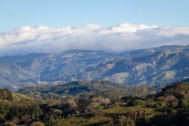 Kosta Rika 'daki San Mateo Dağları' nın geniş manzarası, uzaktaki yemyeşil ormanlar ve bulut katmanlarıyla kaplıdır..