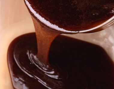 Yapışkan pekmezli zencefilli kurabiye hamuru karıştırma kabına dökülüyor. Koyu, parlak karışımın dokusunu ve akışını gösteren yakın plan bir görüntü..