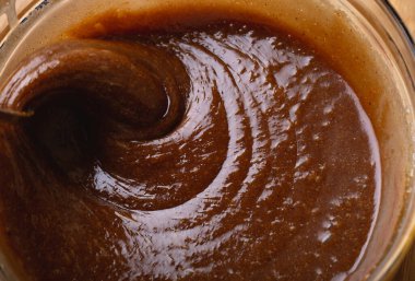 Macro shot 'ta zencefilli kurabiye hamuru karıştırılıyor. Karışım kalın girdaplar oluşturuyor, pişirme hazırlığında dokuyu ve derinliği vurguluyor..