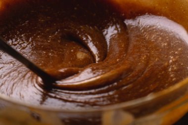 Macro shot 'ta zencefilli kurabiye hamuru karıştırılıyor. Karışım kalın girdaplar oluşturuyor, pişirme hazırlığında dokuyu ve derinliği vurguluyor..