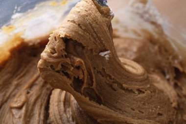 Kalın zencefilli kurabiye hamuru kaşık ya da spatula ile kaldırılıyor, elastik dokuyu ve ayrıntılı girdapları gösteriyor. Tatil pişirmeyi göstermek için ideal..