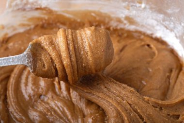 Kalın zencefilli kurabiye hamuru kaşık ya da spatula ile kaldırılıyor, elastik dokuyu ve ayrıntılı girdapları gösteriyor. Tatil pişirmeyi göstermek için ideal..