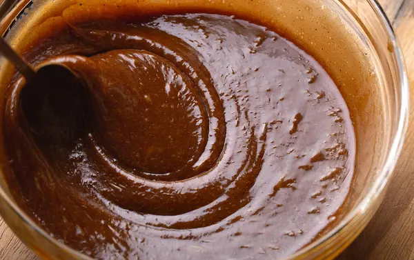 Macro shot 'ta zencefilli kurabiye hamuru karıştırılıyor. Karışım kalın girdaplar oluşturuyor, pişirme hazırlığında dokuyu ve derinliği vurguluyor..