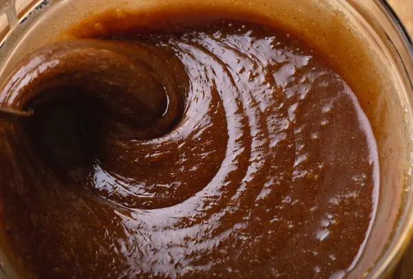 Macro shot 'ta zencefilli kurabiye hamuru karıştırılıyor. Karışım kalın girdaplar oluşturuyor, pişirme hazırlığında dokuyu ve derinliği vurguluyor..