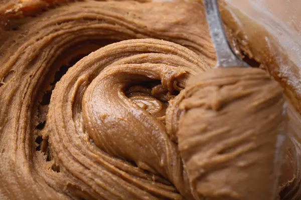 Kalın zencefilli kurabiye hamuru kaşık ya da spatula ile kaldırılıyor, elastik dokuyu ve ayrıntılı girdapları gösteriyor. Tatil pişirmeyi göstermek için ideal..