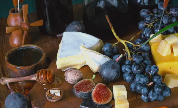 Still life with grapes, honey, figs, cheese, walnuts.