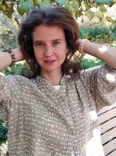 Bahçede kahverengi saçlı ve mavi gözlü beyaz gömlekli genç bir kadın.