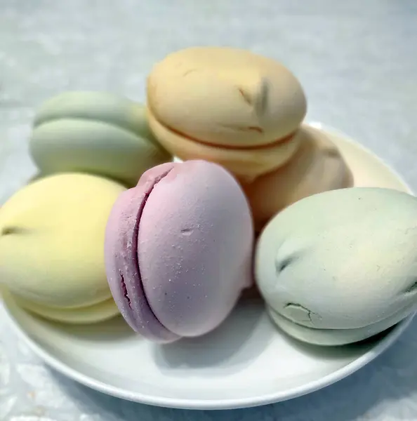 Beyaz bir tabakta çok renkli badem kurabiyeleri (şekerlemeler)