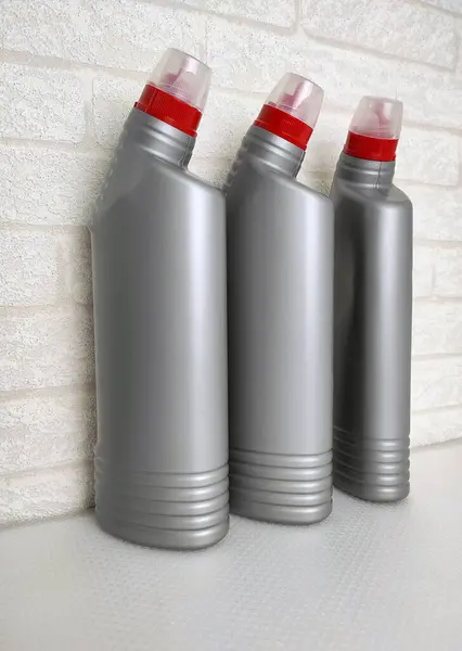Temizlik ürünleri için üç plastik şişe, ev yapımı kimyasallar ya da arka plandaki hafif tuğla duvarlar için tasarlanmış hijyenik ürünler. Reklam ürünlerinde temizlik için uygun, 