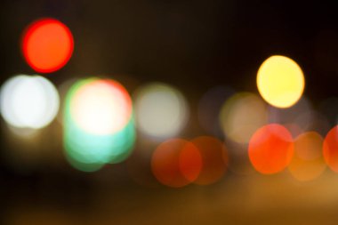 Bulanık renkli dairelerle gece şehir ışıklarının soyut gölgesi. Şehir manzarası kavramları için karamsar ve sanatsal bir zemin oluşturan yumuşak, kırmızı ve sarı ışıklı şehir atmosferi.