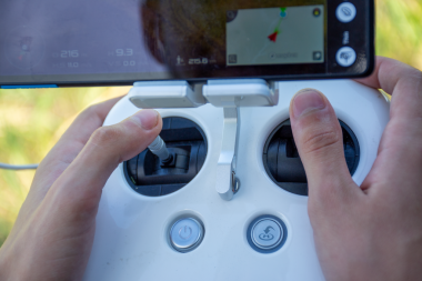 Uzaktan kumandalı ve uçuş verilerini gösteren akıllı telefon ekranlı İHA 'yı kontrol eden ellerin yakın çekimi. Açık hava düzeni, modern teknoloji ve hava seyrüsefer teması yenilik, teknoloji ve macera projeleri için mükemmel.